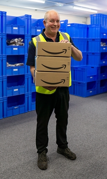The Storage place order fulfilment account manager Richie standing in a room holding Amazon prime delivery boxes