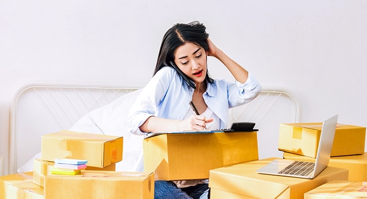 A woman surrounded by packages considering to outsource your order fulfilment